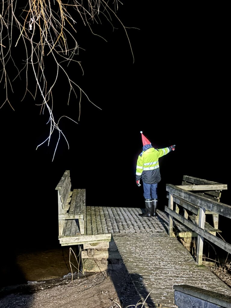 A mysterious elf-like figure standing on a pier by Lake Saimaa in Puumala at night